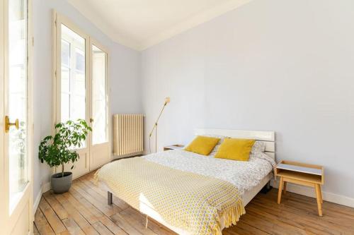 - une chambre blanche avec un lit et des oreillers jaunes dans l'établissement Appartement cosy hypercentre T3 Graslin, à Nantes