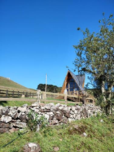 a log cabin with a stone wall and a fence at Pousada Emerich in Cambara do Sul