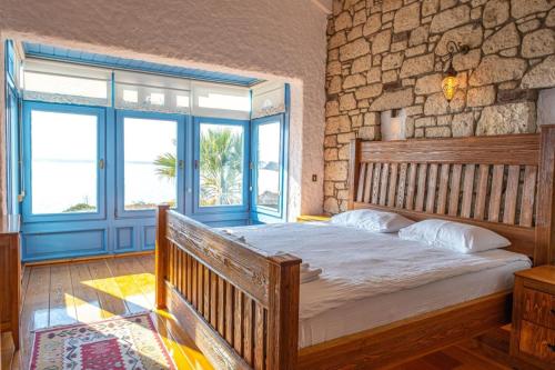 ein Schlafzimmer mit einem großen Bett mit einer Steinwand in der Unterkunft Fener burnunda Denize sıfır orjinaltaş malikane in Cesme