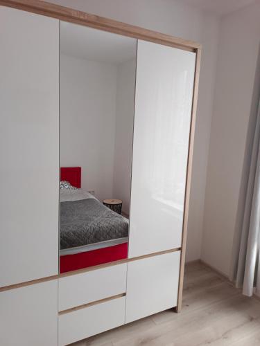 a bedroom with a large white wardrobe with a mirror at Apartament 41 in Rumia