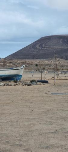 a boat sitting on the sand in a field at Lanzarote Apartment Rental Harbour View in Tías