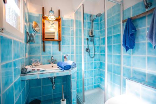 bagno piastrellato blu con lavandino e doccia di VILLA with pool SU PREPPA 'S AUS a Carloforte