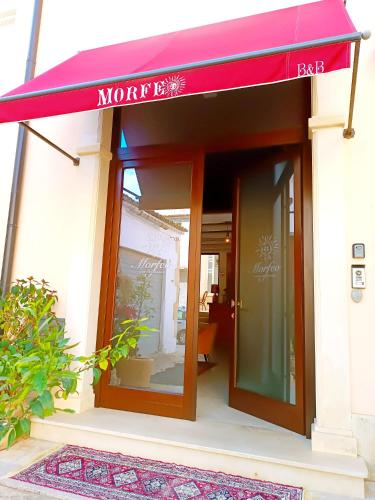 a store with a red awning on a building at Morfeo Charming Rooms & Relax in Avola