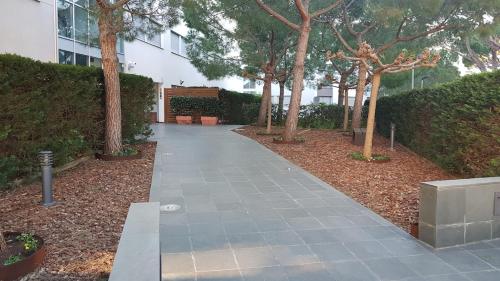 a walkway in a park with trees and a building at Penthouse in Platja d Aro Front Sea with Parking in Platja  d'Aro