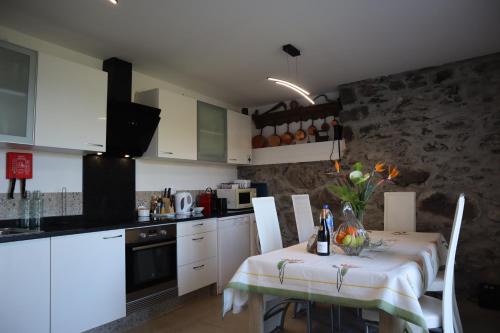 a kitchen with a table and a kitchen with white cabinets at Casa do Tio Albino II, By OP in Ponta Delgada
