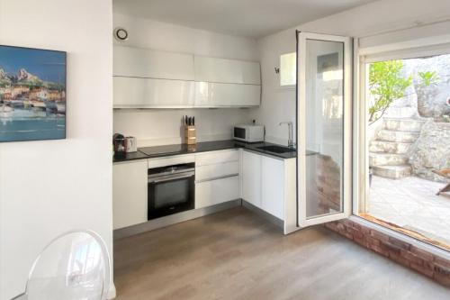 une cuisine avec des placards blancs et une porte coulissante en verre. dans l'établissement Maison chaleureuse au cœur des Calanques de Marseille + jardin., à Marseille