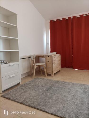Cette chambre comprend un bureau, une chaise et un rideau rouge. dans l'établissement studio Bordeaux, proximité to tram A, à Mérignac