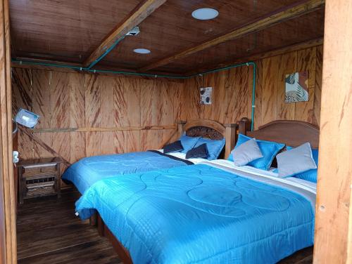 a bedroom with two beds in a wooden room at Finca El Encanto del Guejar in Lejanías