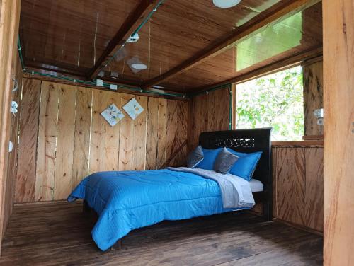 a bed in a room with a wooden wall at Finca El Encanto del Guejar in Lejanías
