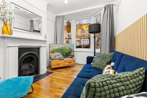 a living room with a blue couch and a fireplace at Amazing House Stratford London in London