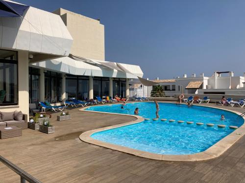 a large swimming pool with people sitting around it at Magnolia Mar Apartamentos in Lagos