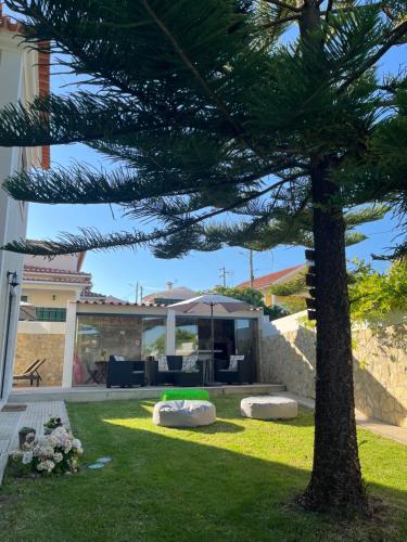 un albero in un cortile con una casa di Ocean Country Guest House Freiria a Freiria