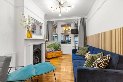 ロンドンにあるAmazing House Stratford Londonの青いソファと暖炉のあるリビングルーム