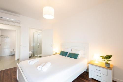 a white bedroom with a large white bed and a bathroom at Wave of happiness in São Martinho do Porto