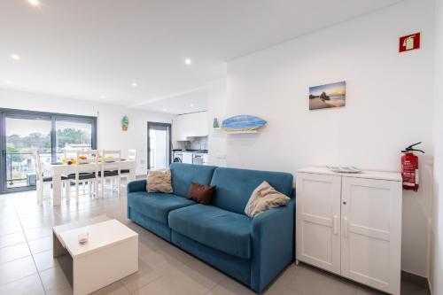 a living room with a blue couch and a kitchen at Wave of happiness in São Martinho do Porto