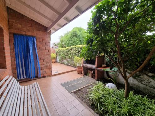 a patio with a bench and a tree and a door at Casa Mardel in Mar del Plata