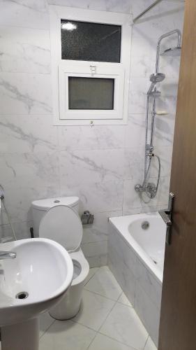 une salle de bain blanche avec toilettes et lavabo dans l'établissement برج الواحه 2, à Ajman
