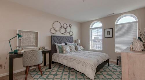 een slaapkamer met een bed en een bureau en twee ramen bij National at Clarendon Metro in Arlington