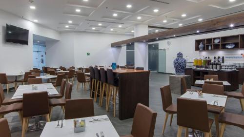 a restaurant with tables and chairs and a room with a bar at Holiday Inn Express Puebla by IHG in Puebla