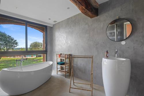 La salle de bains est pourvue d'une baignoire blanche et d'une fenêtre. dans l'établissement La Bastide du Bonrepos, à Bonrepos-Riquet