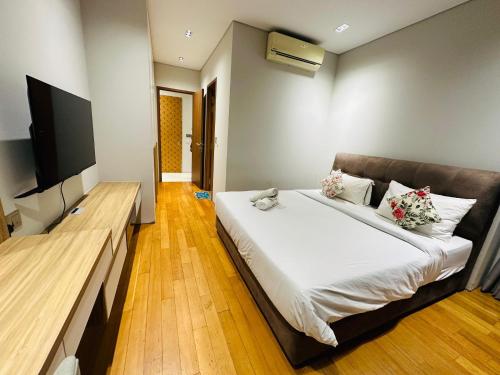 The Apartment Sky Suites KLCC by Ayman في كوالالمبور: غرفة نوم مع سرير وتلفزيون بشاشة مسطحة