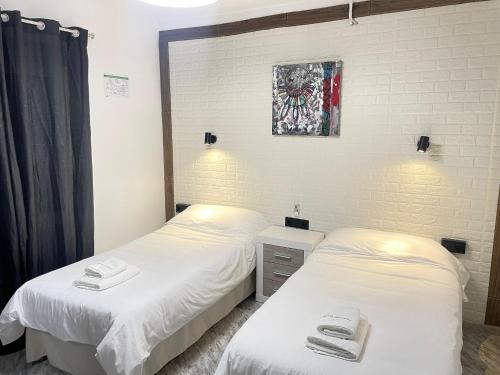 two beds in a room with white sheets at Hotel Arganda in Arganda del Rey
