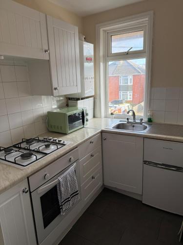 a kitchen with a stove and a sink and a microwave at Private Spacious One-Bedroom Flat - Located Between the City Centre and the New Forest in Totton