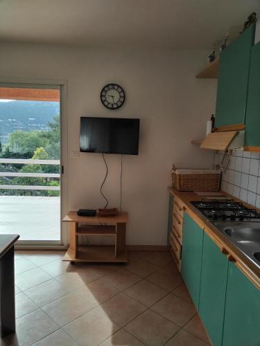 une cuisine avec une cuisinière et une horloge au mur dans l'établissement Villa individuelle avec jardin, à Sartène