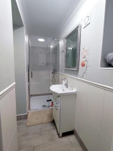 a white bathroom with a sink and a shower at Apartamenty u Antka in Nowe Miasto Lubawskie