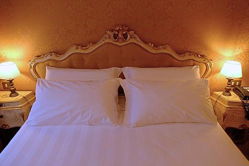 a bed with white pillows and two lamps on two tables at H O T E L S A N G A L L O l in Venice