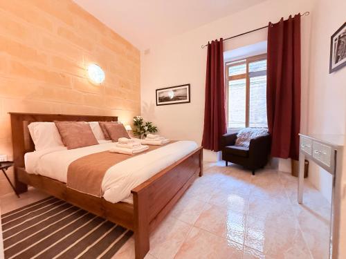a bedroom with a large bed and a chair at Gardjola House by Holi in Senglea