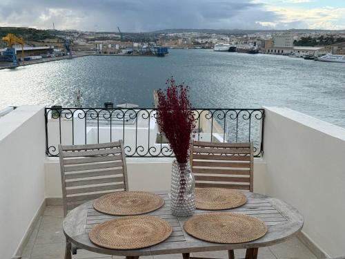 a table with two chairs and a vase with flowers on a balcony at Gardjola House by Holi in Senglea