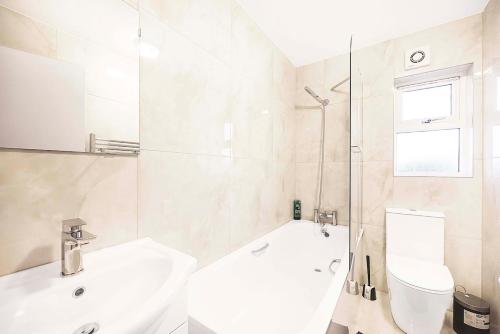 a bathroom with a tub and a sink and a toilet at Stylish London Flat - 5 Sleeper in Ilford