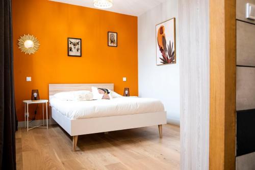 une chambre avec un lit avec un mur orange dans l'établissement Bel appartement entre Campus 1 et Vaugueux, à Caen