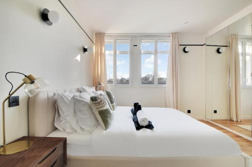 - une chambre blanche avec un grand lit blanc et des fenêtres dans l'établissement La Maison Bizot 52 T2 by Ecoflats, à Paris