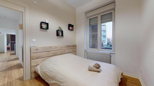 une chambre blanche avec un lit et une fenêtre dans l'établissement Le Majestic & Pool Mulhouse, à Mulhouse