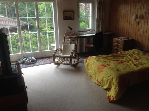 a bedroom with a bed and a chair and windows at good Atmosphere near City and Nature in Pffaffhausen