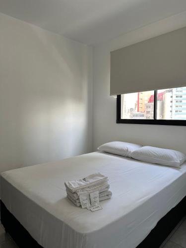 a white bed with white sheets and a window at TrevizZo Catedral da Sé in São Paulo