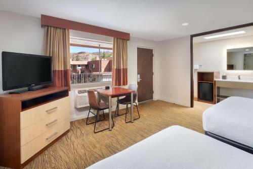 a hotel room with a bed and a desk with a television at Best Western Red Hills in Kanab
