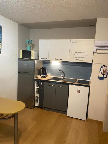 - une cuisine avec des placards blancs, un évier et une table dans l'établissement LES GABIANS - Appartement T2 - TIKI PLAGE - Saint Raphaël, à Saint-Raphaël
