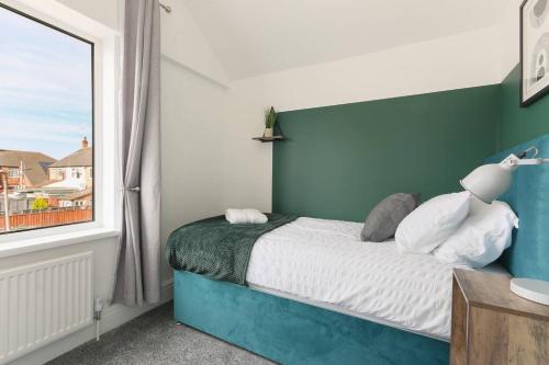 a bedroom with a blue and white bed with a window at Modern home near Alexandra Dock in Great Coates