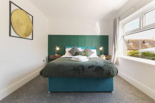 a bedroom with a large bed with a green headboard at Modern home near Alexandra Dock in Great Coates