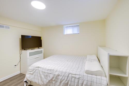 a white bedroom with a bed and a flat screen tv at 1 Mi to Metro DC Area Apt with Fenced Yard! in Silver Spring