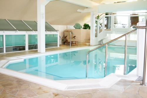 a swimming pool in a house with an open ceiling at Hotel An der Wasserburg in Wolfsburg