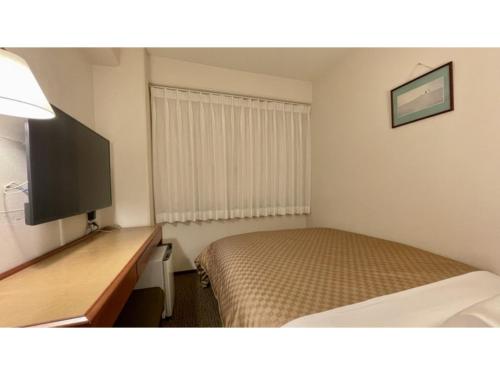 Una habitación de hotel con una cama, un escritorio y un televisor. en Kusatsu Daiichi Hotel - Vacation STAY 99284v, en Kusatsu