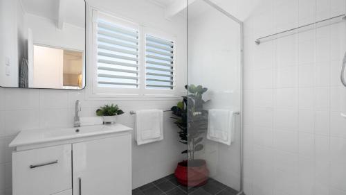 a white bathroom with a sink and a mirror at Casa Blu in Culburra Beach