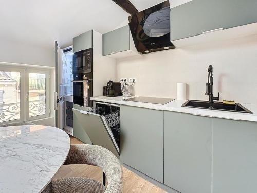 une cuisine avec des armoires blanches et une table dans l'établissement 54m2 hypercenter, face Palais des Festivals, à Cannes