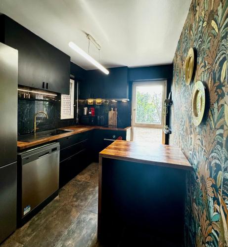 une cuisine avec des armoires noires et un comptoir en bois dans l'établissement La Galerie - appartement entier -75 m2, à Noisy-le-Grand