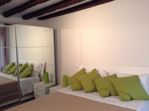 1 dormitorio con cama con almohadas verdes y espejo en Nel Cuore Di Venezia, en Venecia