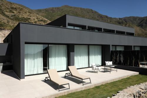 a black house with chairs and a patio at Puesto del Indio in Mendoza